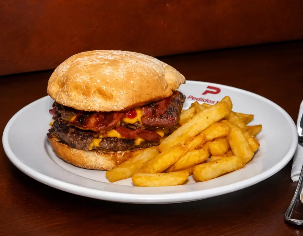 Hamburguesa doble con queso y tocino acompañada de papas fritas