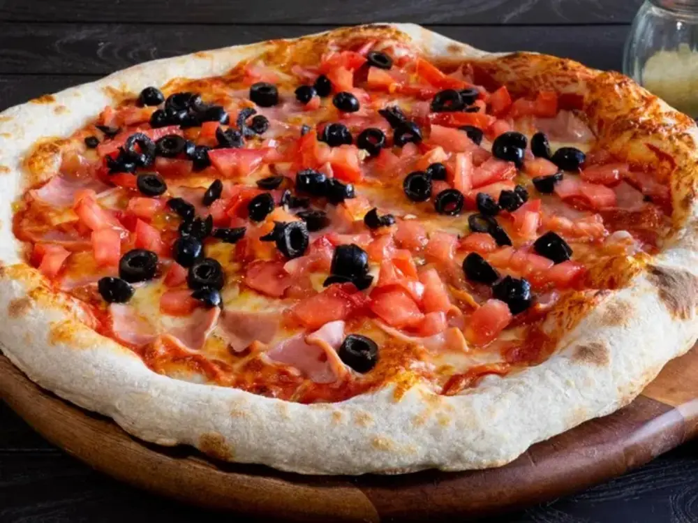 Pizza artesanal con jamón, tomate y aceitunas negras