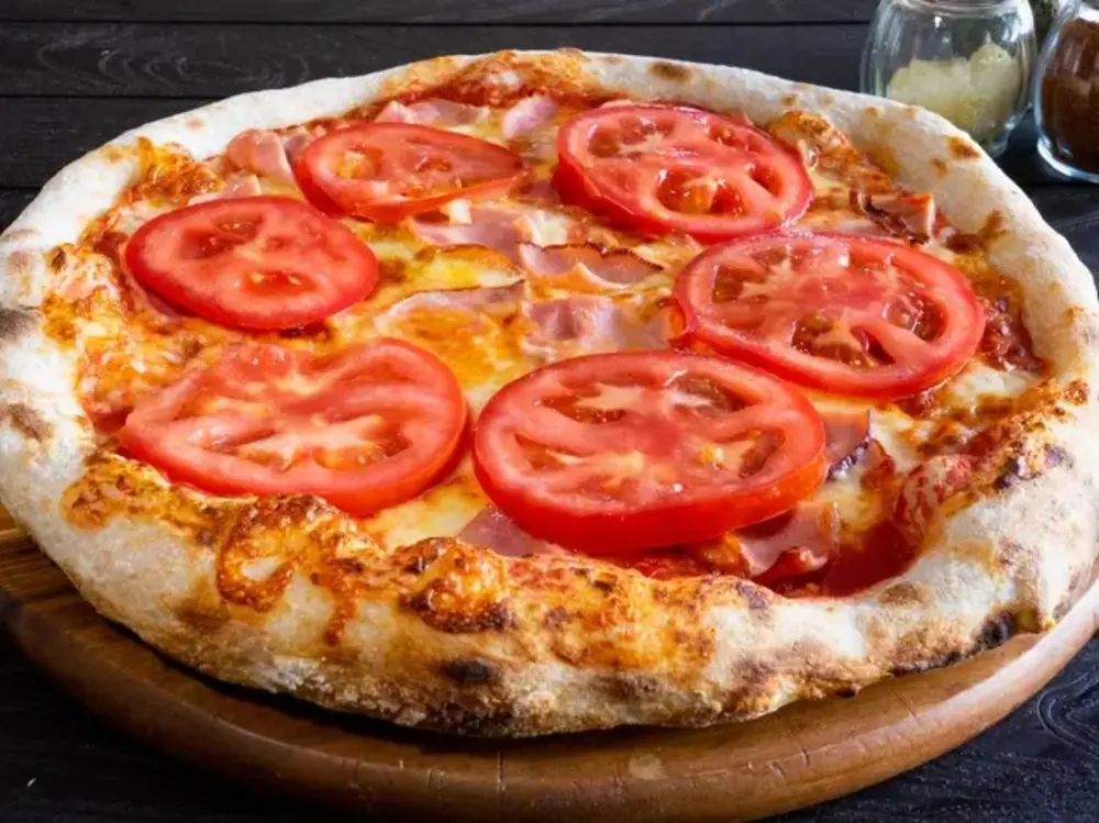 Pizza artesanal con jamón y rodajas de tomate